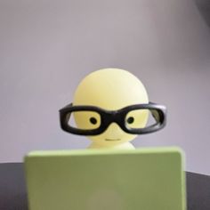 a small toy with glasses sitting in front of a laptop