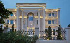 a large white building with many windows and lights on it's front entrance at night