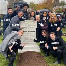 a group of people posing in front of a grave