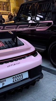 a pink sports car parked next to a black truck