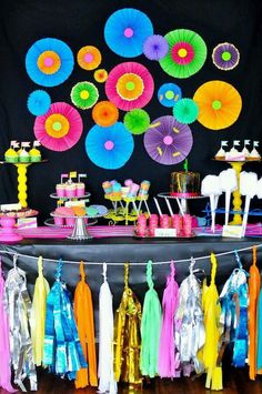 a table topped with lots of different colored paper fans and tassels on top of it