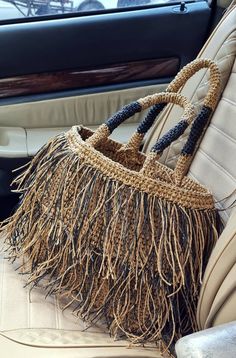 a purse sitting on the back seat of a car with fringed material in it