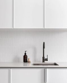 a kitchen with white cabinets and black faucet on the counter top next to a sink