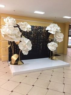 white flowers on display in front of a black and gold wallpapered room with tiled flooring