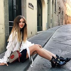 a woman is sitting on the curb with her legs crossed