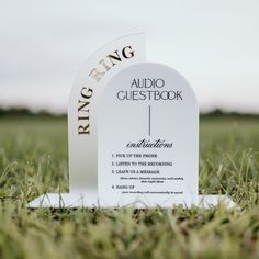 a white sign sitting in the middle of a grass covered field next to a green field