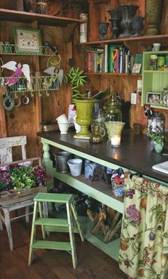 an old fashioned kitchen with lots of pots and pans on the counter, along with two stools