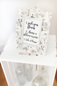 a white frame with writing on it sitting on top of a shelf next to bottles