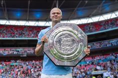 a man holding up a trophy in front of a stadium full of people and fans