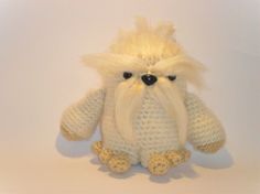 a crocheted white stuffed animal sitting on top of a white table next to a wall