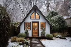 a small white house sitting in the middle of a snow covered yard