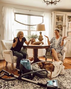 two women sitting at a table with vacuums and cleaning equipment