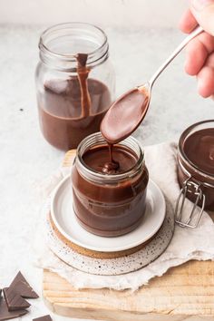 a person spooning chocolate into a jar