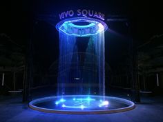 a fountain that is lit up in the dark with blue and white lights on it