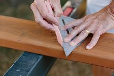 a person using a knife to cut something on top of a piece of plywood