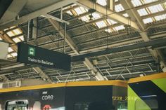 the inside of a train station with several signs hanging from it's ceiling and two trains parked in front of them