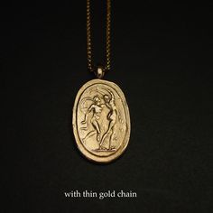 a gold necklace with an image of a woman holding a bird on it's back