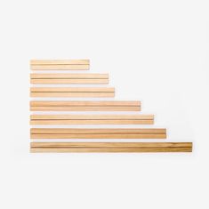 a wooden stair case sitting on top of a white wall next to a piece of wood