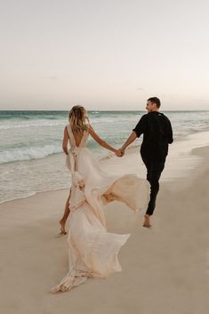 a man and woman walking on the beach holding hands