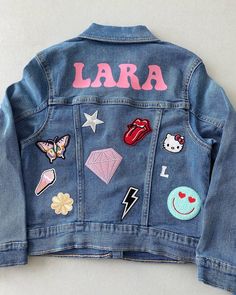 Custom jean jackets  with name and Patches  Name is iron on vinyl  and I apply 7-8 Patches  I love working personally with my customers  we can talk about what your kid loves and what kind of patches you would like to be applied Cute Denim Jacket With Patches For Fall, Cute Patched Denim Jacket For Fall, Trendy Denim Blue Jacket With Patches, Trendy Denim Jacket With Patches, Iron On Patches Jacket, Iron On Patches Ideas Clothes, Iron On Patch Ideas Clothes, Customizable Cute Denim Jacket, Cute Denim Outerwear With Patches