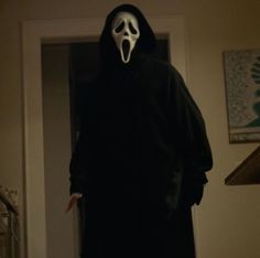 a person in a black hooded jacket with a ghost mask on