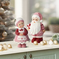 two figurines are standing on a counter next to a christmas tree and ornaments