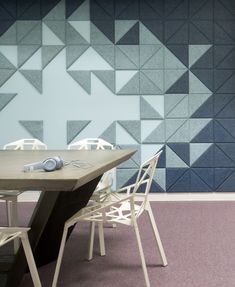 a table and chairs are in front of a wall with geometric designs on the walls