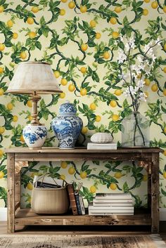 a table with two vases and a lamp on it next to a wallpaper