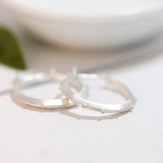 "These are a larger, bolder version of a similar, more delicate hoop found in my shop. Like those, these have a wonderfully modern, classic sensibility to them. They're the kind of earrings you'll want to wear every day and never want to take off. Simple yet striking, they hang just below the earlobe and are very lightweight. The clean lines of this triangular sterling silver hoop are broken only by seven delicate, evenly spaced 14k gold droplets. The sterling ear wire is hinged on one side and Dainty Hoop Wrap Earrings As Gift, Delicate Silver Hoop Earrings For Anniversary, Dainty Small Hoop Wrap Earrings As Gift, Handmade Hoop Earrings For Everyday Wear, Handmade Everyday Hoop Earrings, Nickel-free Small Hoop Earrings For Anniversary, Delicate Small Hoop Pierced Earrings, Delicate Silver Hoop Jewelry, Delicate Hoop Earrings For Anniversary