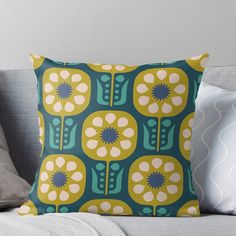 a blue and yellow pillow with flowers on it sitting on a couch next to pillows