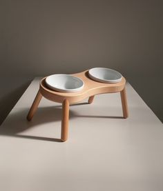 two bowls sit on top of a wooden stand in the shape of a dog bowl