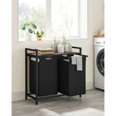 a laundry room with two black bins and a washing machine in front of the window