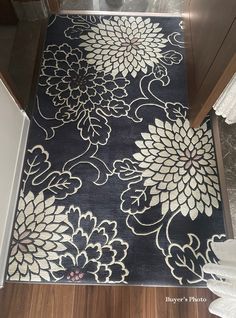 a black and white rug with flowers on it in a hallway next to a door