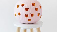 a pink pumpkin decorated with foxes on top of a white stool next to a wall