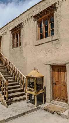 an old building with stairs leading up to it and a lantern in front of the door