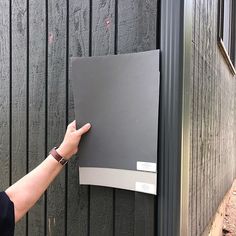 a woman is holding onto the side of a building with her hand on the door