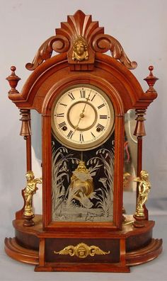 an ornate wooden clock with figures on the front and sides, sitting on a white surface