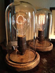 two clear glass lamps sitting on top of a wooden table