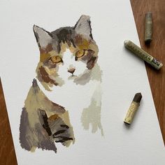 a drawing of a cat on paper next to some crayons