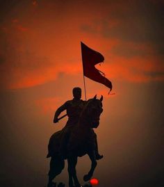 a statue of a man riding on the back of a horse holding a red flag