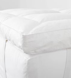 an unmade bed with white sheets and pillows