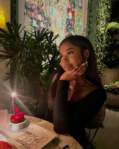 a woman sitting at a table in front of a cake with a candle on it