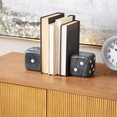 a clock, books and dice on a dresser in a living room or dining room