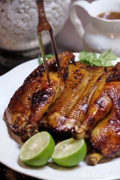 a white plate topped with chicken wings and garnished with limes