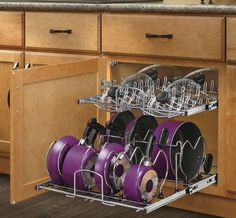 an open dish rack with purple pots and pans in the bottom drawer on a wooden kitchen countertop