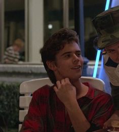 two people sitting at a table with food in front of them and one person wearing a mask