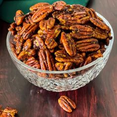 a glass bowl filled with pecans on top of a wooden table