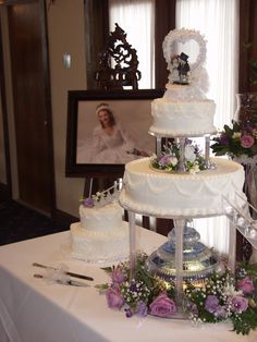 a three tiered wedding cake sitting on top of a white tablecloth covered table