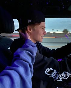 a young man sitting in the driver's seat of a car