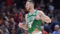 a male basketball player in a green jersey and white shorts is running on the court